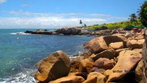 Rocky coast with turquoise sea and vegetation at Praia de Calhetas